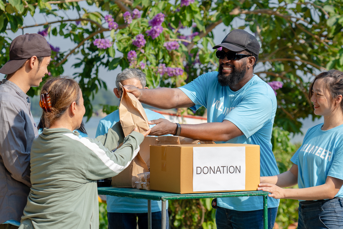 Volunteers distributing donations outdoors with smiles.