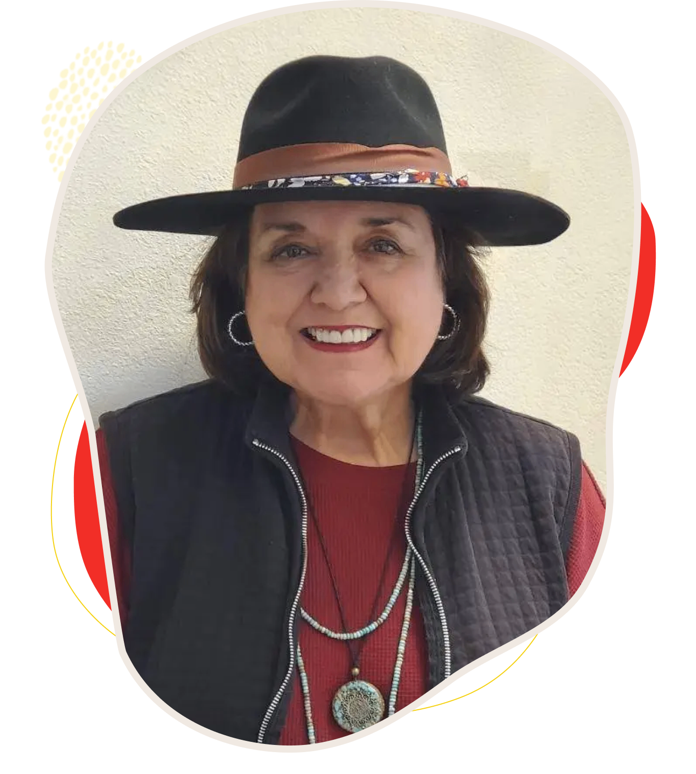 Smiling woman in a black hat and layered necklaces.