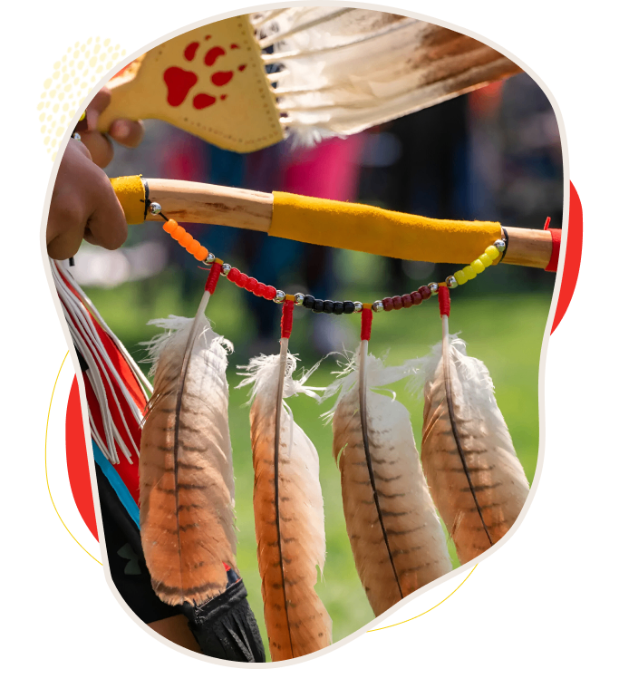 A hand holding a decorative piece with feathers and beads.